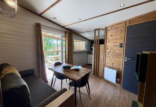 Interno di un lodge a La Clairiere, Campeggio Seasonova Ensoya, Francia, con zona pranzo e vista terrazza.