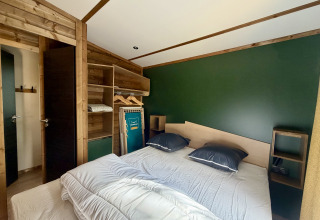 Camera da letto al lodge La Clairiere presso il Campeggio Seasonova Ensoya in Francia, con letto matrimoniale.