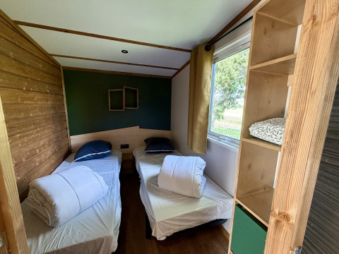 Room with two single beds, window view, and shelf at La Clairiere, Campsite Seasonova Ensoya in France.