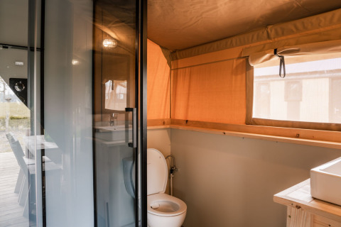 Baño de tienda safari glamping con inodoro, lavabo y ventana en Holiday Park Eigen Wijze, Países Bajos.