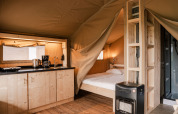 Indretning af en luksuriøs glamping telt med tekøkken, dobbeltseng og varmeovn på Holiday park Eigen Wijze.