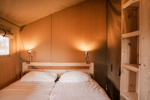 Camera accogliente con letto matrimoniale e scaffali in legno in una tenda safari glamping al Holiday park Eigen Wijze, Paesi Bassi.