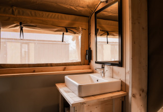 Interno della tenda safari glamping presso Holiday park Eigen Wijze nei Paesi Bassi con lavandino e specchio.
