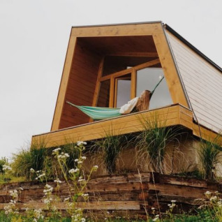 Panorama Glamping – Tiny houses Podravska with modern A-frame tiny house and hammock in scenic countryside.