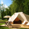 Glamping at Castel Camping le Brevedent in Normandy featuring a large lodge tent, chairs and a natural setting.
