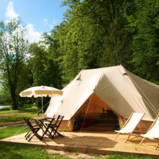 Glamping at Castel Camping le Brevedent in Normandy featuring a large lodge tent, chairs and a natural setting.