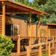 Accessible wooden lodge with spacious terraces, outdoor seating, and ramp at Flower Camping Le Platin, France.