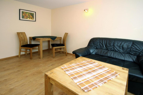 Woonkamer bungalow met houten meubels, zwarte zetel, eettafel en wanddecoratie in Duitsland.