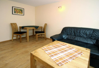 Woonkamer bungalow met houten meubels, zwarte zetel, eettafel en wanddecoratie in Duitsland.