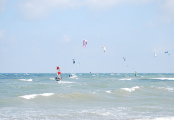 Windsurfers and kitesurfers enjoying the waves near Am Strand lodge in Germany on a bright day.