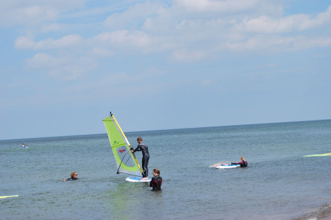 Verschillende mensen windsurfen bij de kust voor lodge «Am Strand» in Duitsland op een zonnige dag.