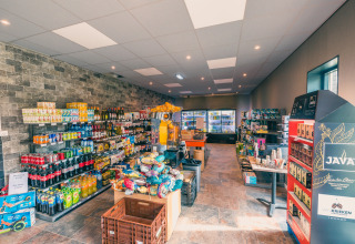 Tienda en una cabaña con bebidas, refrigerios, café y refrigeradores al fondo, interior luminoso.