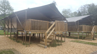 Safari tent with private sanitary facilities at Campsite Vallee de L'Our in Luxembourg, elevated on stilts.