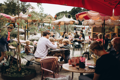 Café en plein air au Camping 'De Kleine Wereld' à Groningue, Pays-Bas, avec des familles et des enfants.