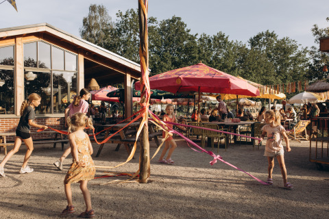 Niños juegan con cintas de colores alrededor de un poste en el camping De Kleine Wereld en Groningen, Países Bajos.