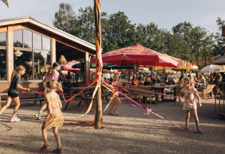 Niños juegan con cintas de colores alrededor de un poste en el camping De Kleine Wereld en Groningen, Países Bajos.