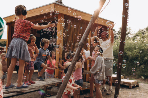 Kinder und Erwachsene spielen mit Seifenblasen auf Camping De Kleine Wereld in Groningen, Niederlande.