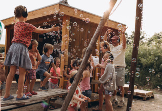 Niños y adultos juegan con burbujas de jabón al aire libre en Camping De Kleine Wereld en Groningen, Países Bajos.