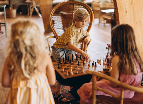 Kinder spielen gemeinsam Schach in einer gemütlichen Holzhütte im Ferienpark «De Kleine Wereld», Groningen.