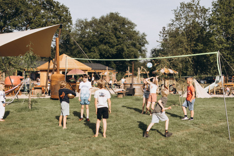 Niños juegan voleibol en el césped del camping De Kleine Wereld, parque de vacaciones en Groningen, Países Bajos.