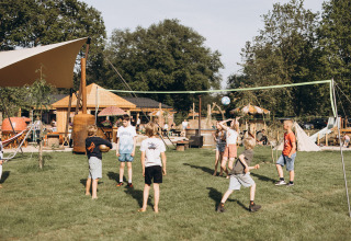 Niños juegan voleibol en el césped del camping De Kleine Wereld, parque de vacaciones en Groningen, Países Bajos.