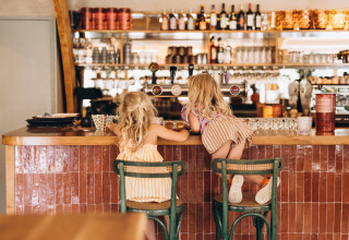 Zwei kleine Kinder sitzen an der Bar des Campingplatzes De Kleine Wereld in Groningen, Niederlande.