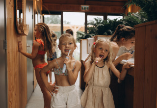 Niños cepillándose los dientes y disfrutando en el parque vacacional Camping De Kleine Wereld en Groningen.
