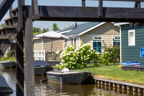 Foto einer Lodge am Wasser, Blumengarten und Boote bei Stern 6 in Giethoorn, Niederlande.