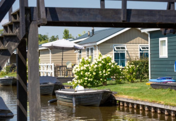 Photo of a waterfront lodge with boats and flowers at Stern 6 in Giethoorn, Netherlands.