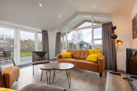 Moderne leefruimte in lodge Schipbeek 6 aan Tolplas, Nederland, met grote ramen en warme aankleding.
