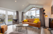 Salon moderne du lodge Schipbeek 6 à Tolplas, Pays-Bas, avec grandes fenêtres et une décoration chaleureuse.