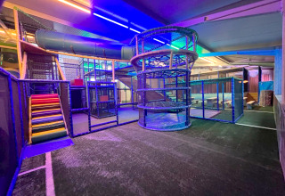 Overdekte speelzone met kleurrijke glijbanen en klimstructuren, verlicht met LED-lampen bij glamping.