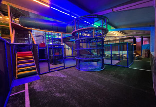 Indoor playground area with colorful slides and climbing structures, lit with LED lights at a glamping site.