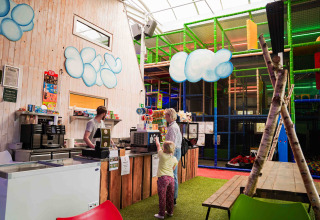 Indoor café and soft play area at a glamping site with a child and adult ordering at the counter.