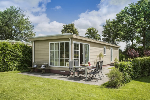 Außenansicht von Chalet 4 im Tolplas, Niederlande, mit Terrasse, Gartenmöbeln und grüner Umgebung.