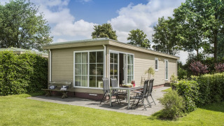 Außenansicht von Chalet 4 im Tolplas, Niederlande, mit Terrasse, Gartenmöbeln und grüner Umgebung.