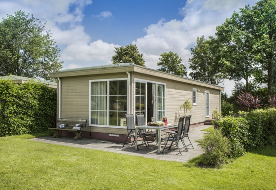 Buitenaanzicht van Chalet 4 bij Tolplas in Nederland, met tuin, zitje en mooie groene omgeving.