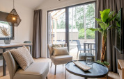 Moderne stue i Tiny House 2 med store vinduer, hyggelig indretning og udsigt til skov ved Bospark 't Wolfsven.