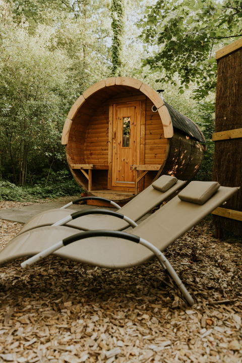Sauna in legno rotonda e due lettini nel bosco, Luxe bosrand loft, Si-Es-An, Paesi Bassi.