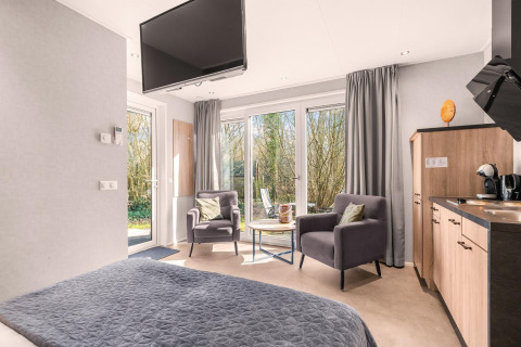 Moderne loft-lejlighed med komfortable stole og udsigt til skov ved Si-Es-An campingplads i Holland.