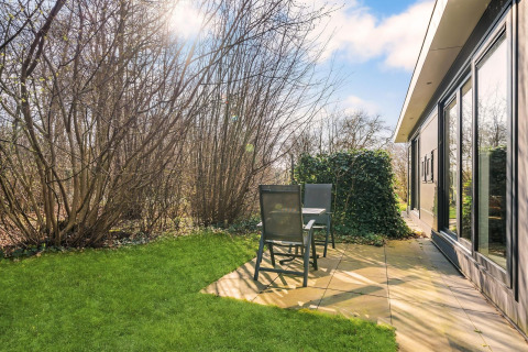 Patio soleggiato con sedie e tavolo al Luxe bosrand loft, immerso nel verde, Si-Es-An, Paesi Bassi.