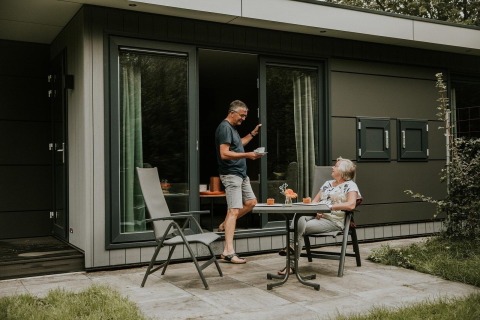 Ein älteres Paar genießt Kaffee vor einem modernen Naturhaus auf einem Campingplatz in den Niederlanden.