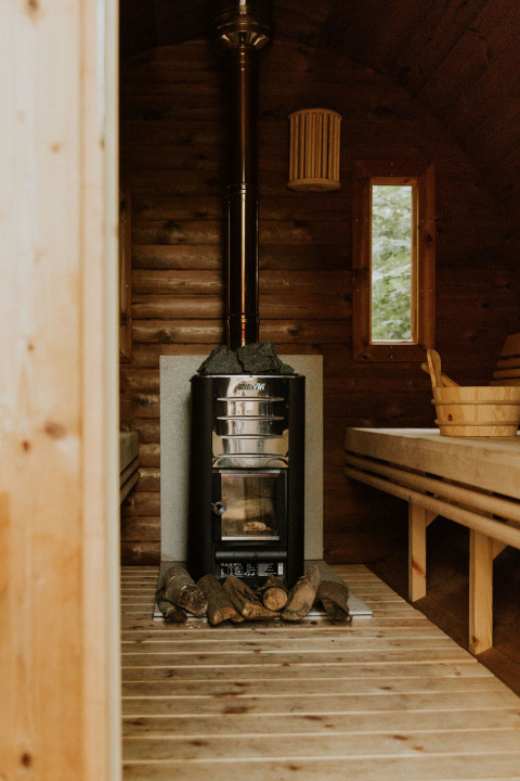Indvendig udsigt til en hyggelig træsauna med brændeovn og bænke på et naturhus i Holland.