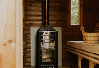 Interior view of a cozy wood sauna with stove and benches at a nature house in the Netherlands.