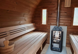 Interior view of a wooden sauna with benches, stove and bucket at a nature house in the Netherlands.