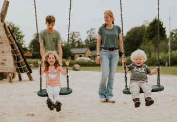 To børn gynger og bliver skubbet af en mand og kvinde på en legeplads på Si-Es-An campingplads i Holland.