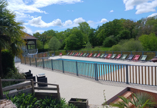 Buitenbad met kleurrijke ligstoelen bij Domaine Papillon, omgeven door groen in Occitanie, Frankrijk.