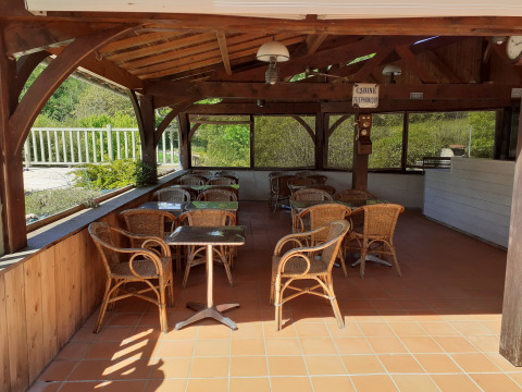 Overdekte zithoek met rotan stoelen bij Domaine Papillon vakantiepark in Occitanie, Frankrijk.
