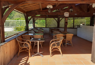 Overdekte zithoek met rotan stoelen bij Domaine Papillon vakantiepark in Occitanie, Frankrijk.