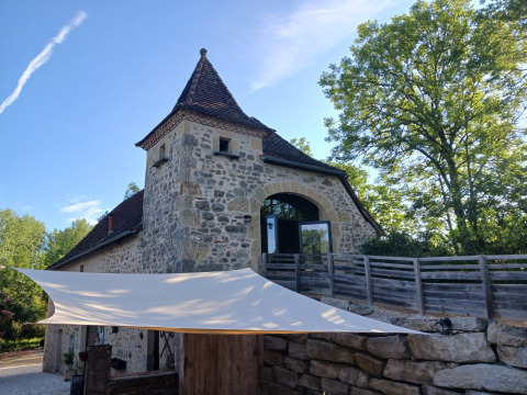 Stenen gebouw met toren en terras in Domaine Papillon vakantiepark in Occitanië, Frankrijk, bij daglicht.
